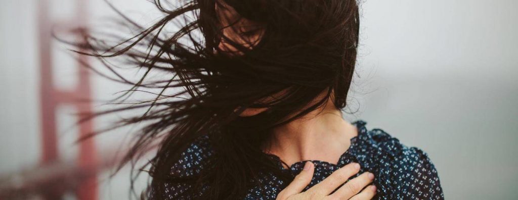 woman hand on chest hair flying covering face