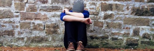 woman sits alone face on knees feeling upset sad depressed