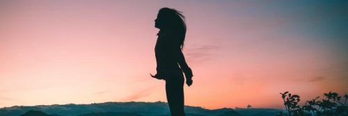 woman shadow stands enjoying cool weather in sunset sky