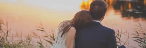 couple sits in peace on grass beside lake while woman lying on boyfriend shoulder