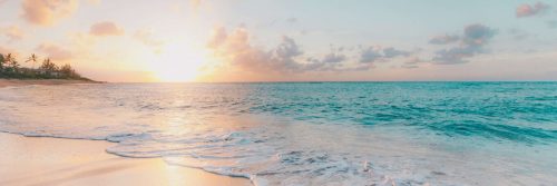 blue ocean light waves covering up sand in sunset sky