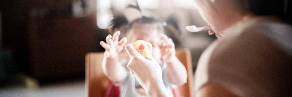 little adorable daughter plays with toy on mother hand