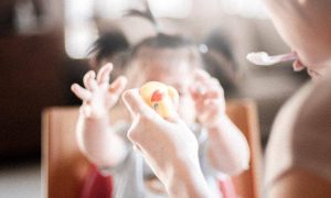 little adorable daughter plays with toy on mother hand