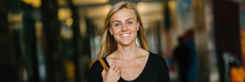 woman carrying back bag happily walks smiling