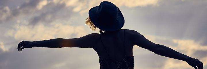 woman facing backward stands gratitude life in blue cloudy sky