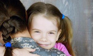 daughter hair tied with blue band happily smiles hugs mom