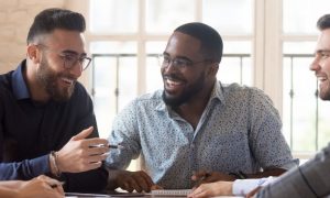 group of mixed genders happily discussing smiling in co working office room