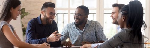 group of mixed genders happily discussing smiling in co working office room