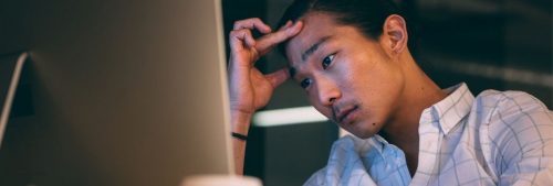 man hand on forehead stressed thinking looking at personal computer