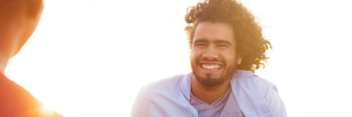 curly hair man smiles in sunny sky