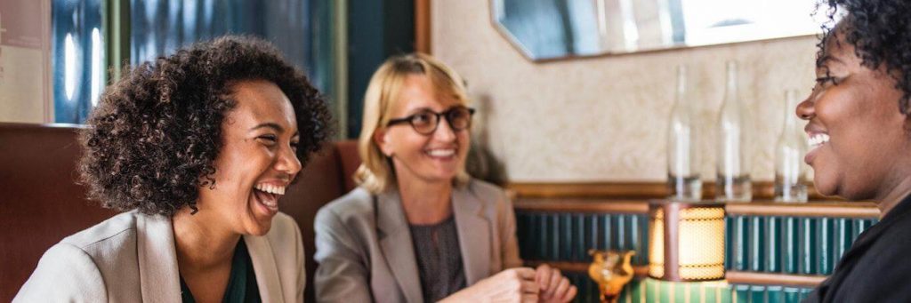 three women sit on luxury restaurant talking laughing