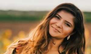 woman stands on field happily smile in sunny sky