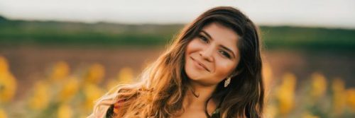 woman stands on field happily smile in sunny sky