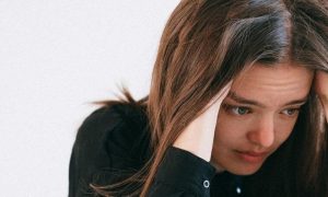 woman hands on face sadly looks at laptop