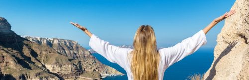 woman gratitude earth blue ocean sky white shirt blonde coast rocks