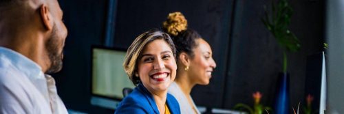 two women sit in office smiling at man sitting beside