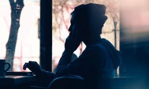 man sits alone in office focuses on work beside mug