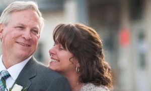 married elderly couple stands on street happily smiling