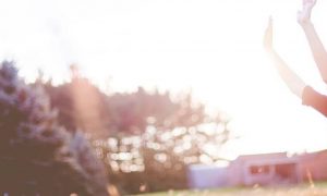 woman happily stands on field raising hands gratitude life in beautiful sunny sky