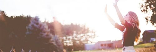 woman happily stands on field raising hands gratitude life in beautiful sunny sky