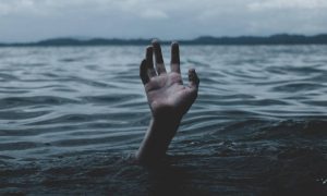 hand raises over water ocean in overcast weather