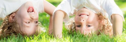 two girls stand heads on green field smiling having fun in park