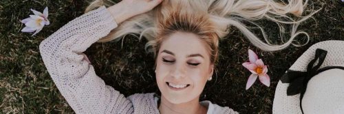 woman lies on grass eyes closed happily smiling gratitude life