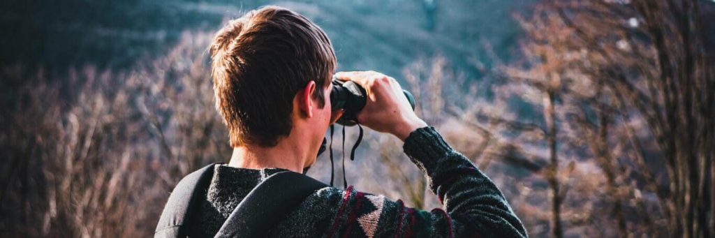 man looking forest through binocular vision