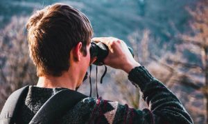 man looking forest through binocular vision