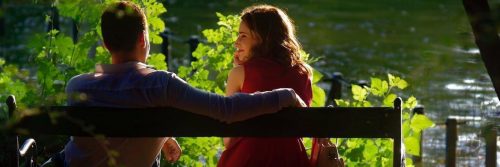 couple sits on bench happily smiling beside lake