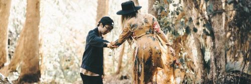 woman helping young man walk in forest