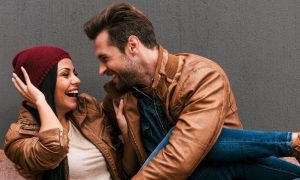 couple sits on bench happily talking laughing