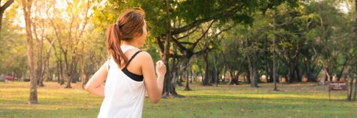 woman exercises jogs in park in sunny sky