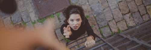 woman about to climb stair raises hand asking for help support