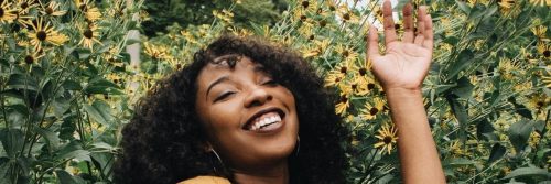 curly hair woman lies on sunflower garden happily smiling immersing into nature