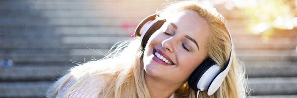 woman wears headphones listening to music happily smiling