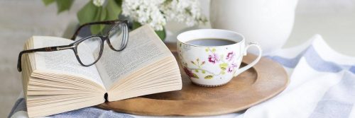 book and white flowerful black prescription glasses on small timber table