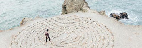 man walking within maze on rock beside beach