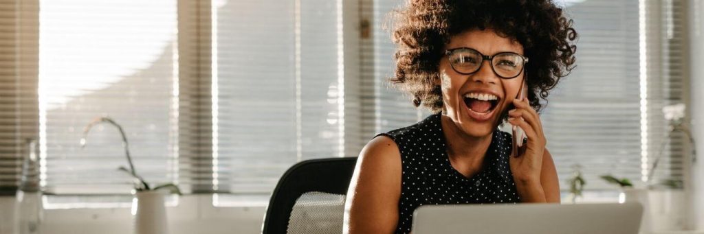 woman happy exciting face answering phone while sitting in office