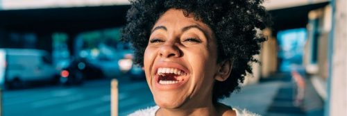 curly black hair woman happy face walks in car park laughing