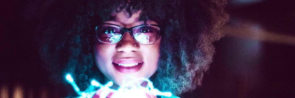 curly black hair woman happily smiles carrying lighting bulbs