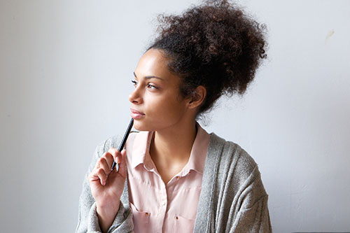 Woman thinking about her feelings and reflecting with pencil