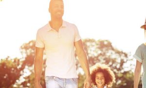 parents little adorable daughter holds hand walking happily in park in beautiful sunny weather