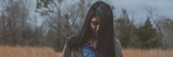 woman stands alone on field feeling sad