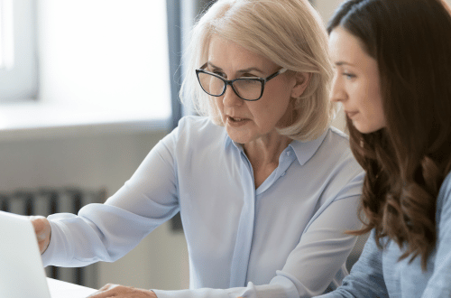 A young woman with long brown hair being mentored by an older woman.