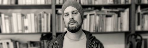 man wearing winter hat stands in library