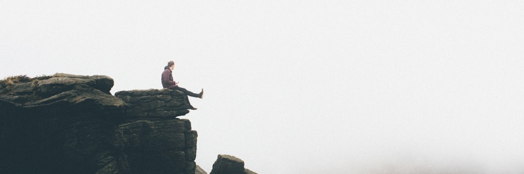 man sits alone on dick looking at foggy sky