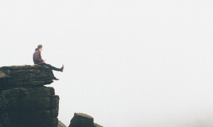 man sits alone on dick looking at foggy sky