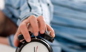 man sleeps while holding clock