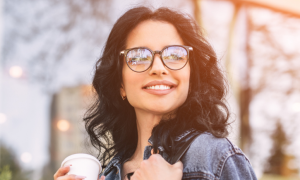 long curly black hair lady happily smiles hand holding white cup